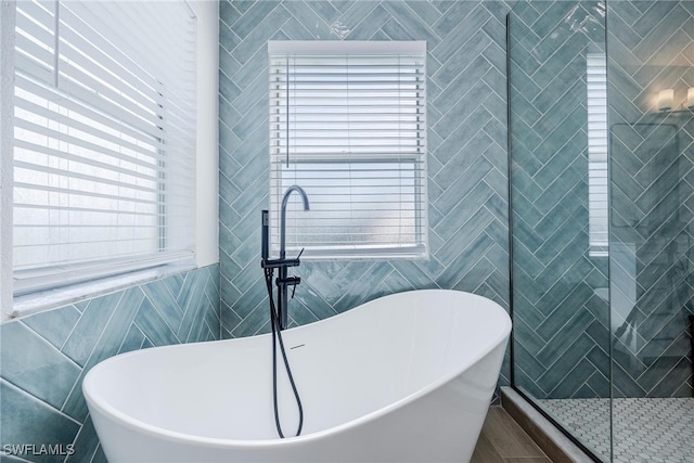 bathroom with a bathing tub and tile walls