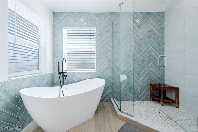 bathroom featuring plus walk in shower, tile patterned flooring, and tile walls