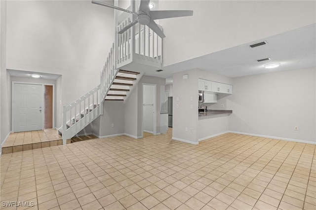 unfurnished living room featuring a high ceiling, light tile patterned floors, ceiling fan, and sink