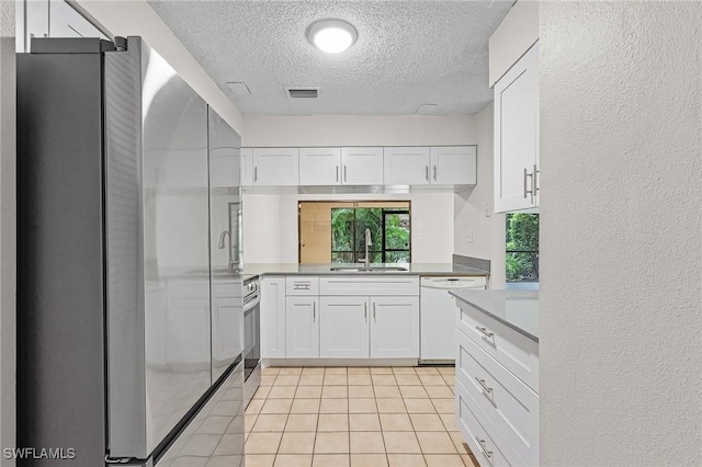 kitchen with a textured ceiling, stainless steel appliances, sink, light tile patterned floors, and white cabinets