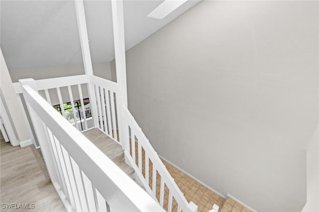 staircase featuring hardwood / wood-style flooring and lofted ceiling with skylight