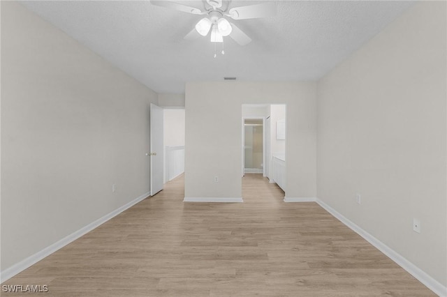 unfurnished bedroom featuring light wood-type flooring, a textured ceiling, ceiling fan, a spacious closet, and a closet