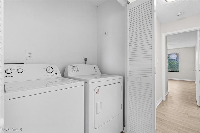 laundry room with a textured ceiling, light hardwood / wood-style floors, and washer and clothes dryer