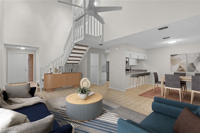 tiled living room with ceiling fan, a towering ceiling, and sink