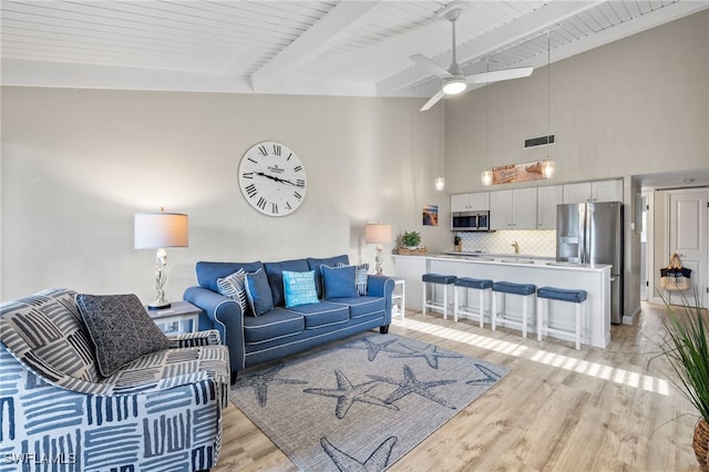 living room featuring ceiling fan, beamed ceiling, light hardwood / wood-style floors, and wooden ceiling