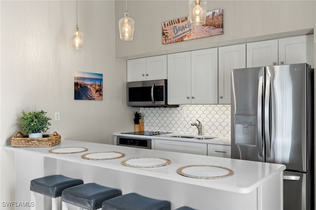 kitchen featuring decorative backsplash, white cabinetry, stainless steel appliances, decorative light fixtures, and sink