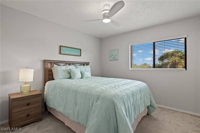 carpeted bedroom with ceiling fan and a textured ceiling