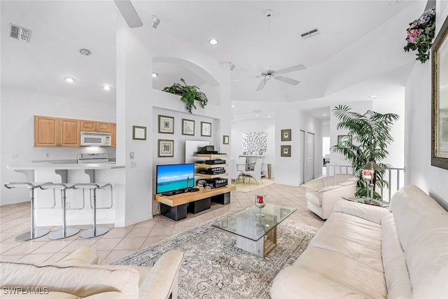 tiled living room with ceiling fan and a towering ceiling