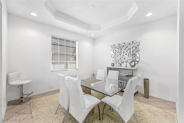 dining area with light tile patterned flooring, ornamental molding, and a tray ceiling