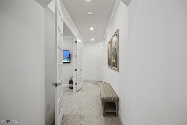 hallway with ornamental molding and light tile patterned floors