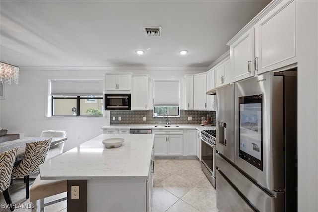 kitchen featuring stainless steel appliances, light tile patterned floors, a center island, sink, and white cabinets