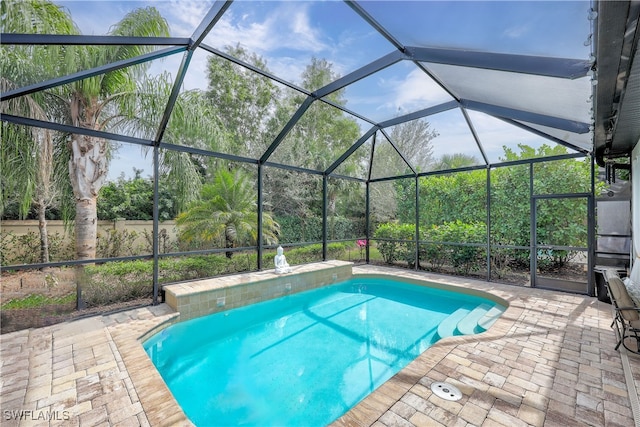 view of swimming pool featuring glass enclosure and a patio area