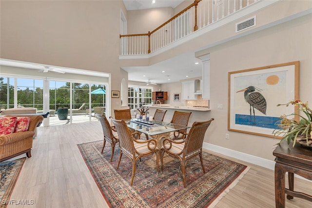 dining area featuring high vaulted ceiling, light wood-type flooring, and ceiling fan