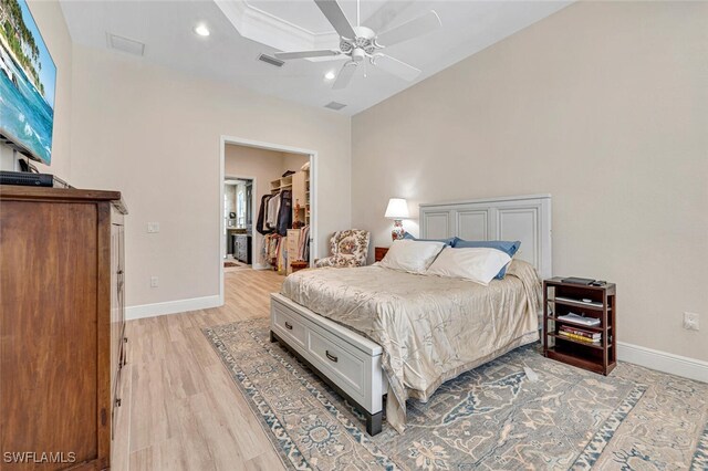 bedroom featuring light wood-type flooring, ceiling fan, a walk in closet, and a closet