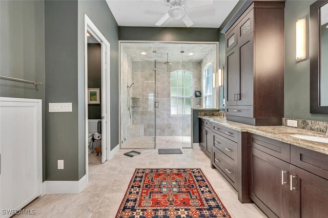 bathroom with toilet, a shower with door, ceiling fan, and vanity