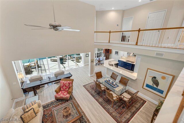 living room featuring a towering ceiling, ceiling fan, and hardwood / wood-style flooring