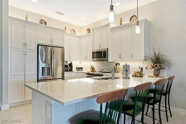 kitchen featuring pendant lighting, a breakfast bar, white cabinets, appliances with stainless steel finishes, and kitchen peninsula