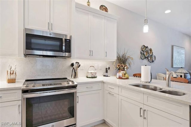 kitchen featuring pendant lighting, sink, decorative backsplash, appliances with stainless steel finishes, and white cabinetry