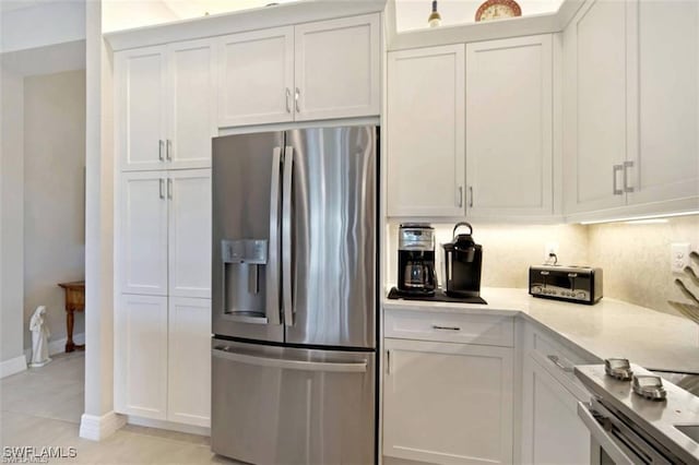 kitchen with decorative backsplash, white cabinetry, light tile patterned flooring, and stainless steel refrigerator with ice dispenser