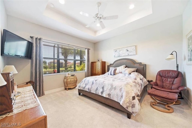 carpeted bedroom with a tray ceiling and ceiling fan