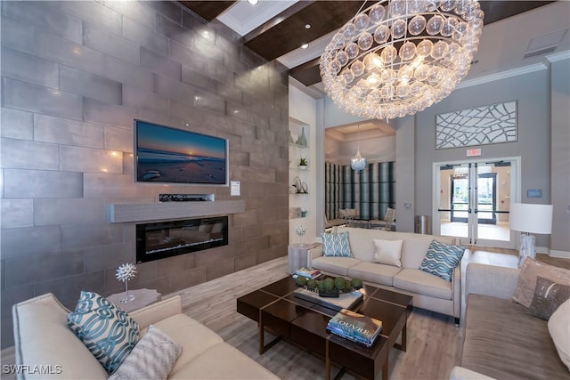 living room with a tile fireplace, french doors, ornamental molding, tile walls, and a notable chandelier