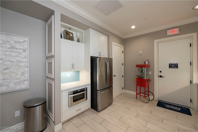 kitchen featuring backsplash, crown molding, white cabinetry, and stainless steel appliances