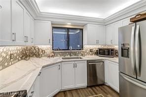 kitchen featuring ornamental molding, appliances with stainless steel finishes, a sink, and tasteful backsplash