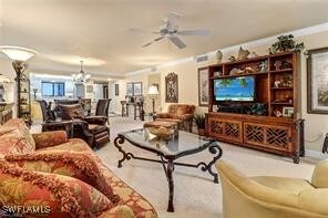 living room with ceiling fan with notable chandelier and ornamental molding