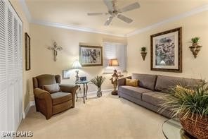 carpeted living area featuring ceiling fan, ornamental molding, and baseboards