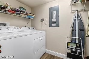 washroom featuring laundry area, electric panel, baseboards, wood finished floors, and independent washer and dryer