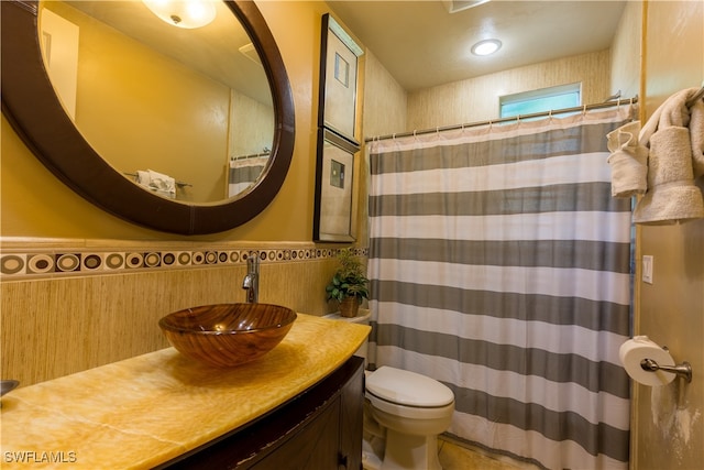 bathroom with curtained shower, tile walls, toilet, and vanity