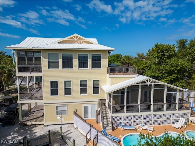 rear view of house with a balcony and a sunroom