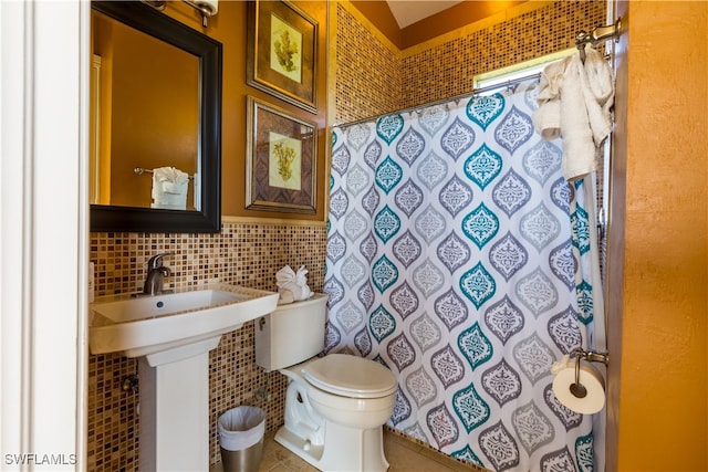 bathroom with toilet, tile patterned flooring, backsplash, curtained shower, and tile walls