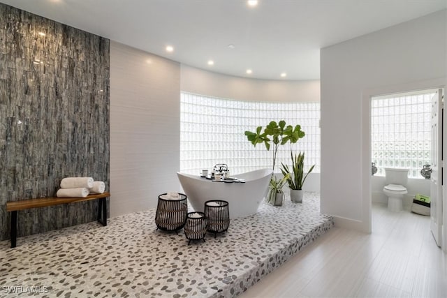 bathroom featuring toilet, tile walls, and a bathing tub