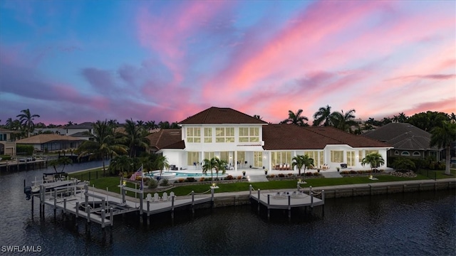 back house at dusk featuring a water view and a patio area