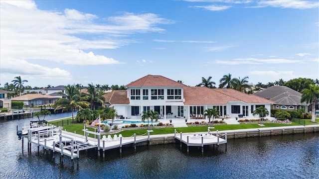 back of property with a patio, a pool, a water view, and a lawn