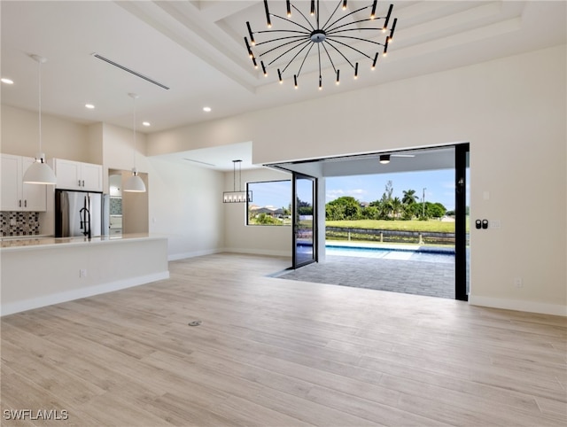 unfurnished living room featuring a raised ceiling and light hardwood / wood-style flooring