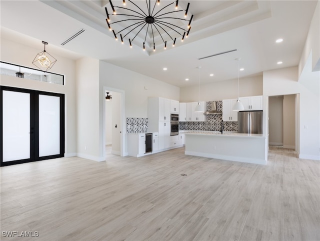 unfurnished living room featuring wine cooler, french doors, a high ceiling, and light hardwood / wood-style flooring