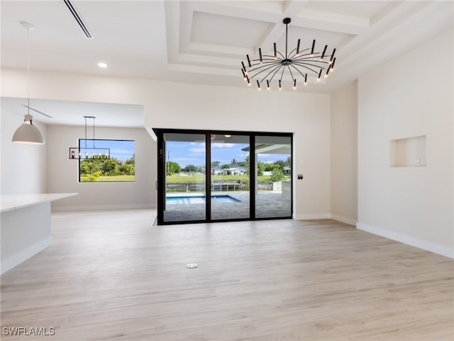 empty room featuring light wood-type flooring, coffered ceiling, a notable chandelier, and a healthy amount of sunlight