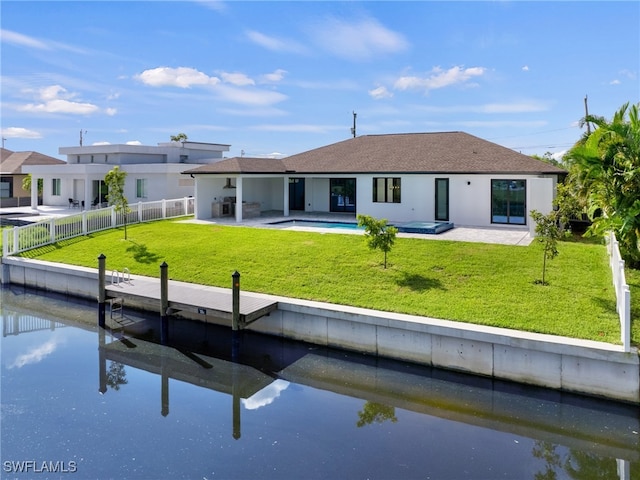 rear view of house featuring a water view, a yard, and a patio area