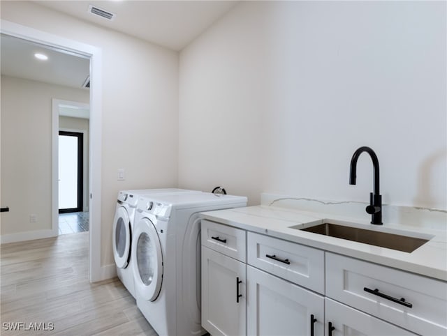 laundry room featuring cabinets, washer and dryer, sink, and light wood-type flooring