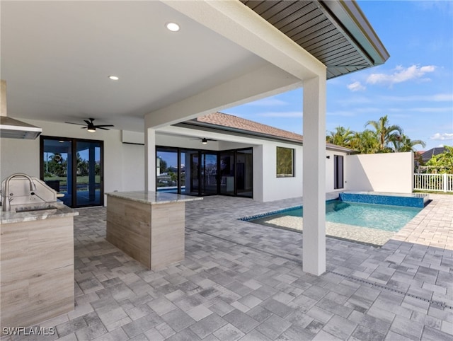 view of swimming pool with sink, a wall mounted air conditioner, ceiling fan, a patio, and exterior kitchen