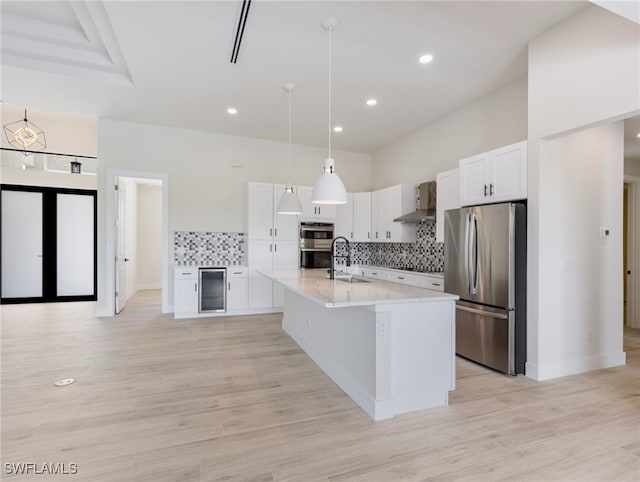 kitchen featuring appliances with stainless steel finishes, tasteful backsplash, hanging light fixtures, light hardwood / wood-style flooring, and white cabinets