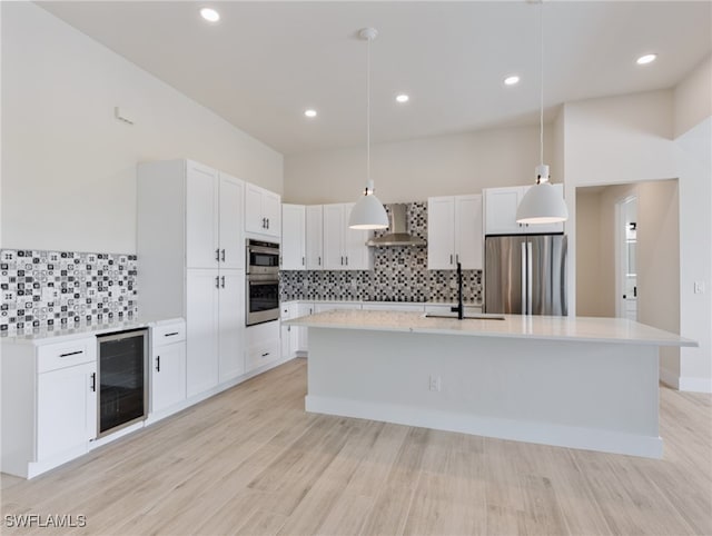 kitchen with white cabinets, wall chimney range hood, pendant lighting, appliances with stainless steel finishes, and wine cooler