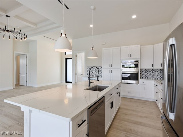 kitchen featuring stainless steel appliances, white cabinetry, pendant lighting, and a kitchen island with sink