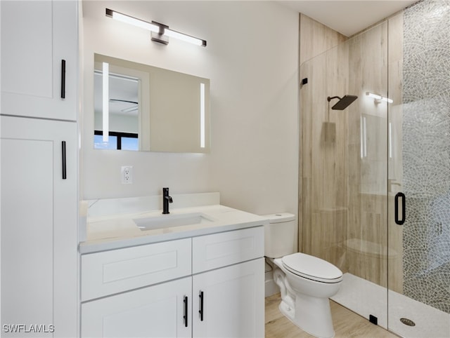 bathroom with hardwood / wood-style flooring, a shower with door, vanity, and toilet