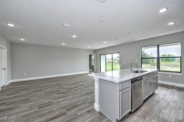 kitchen with sink, plenty of natural light, dishwasher, gray cabinets, and an island with sink