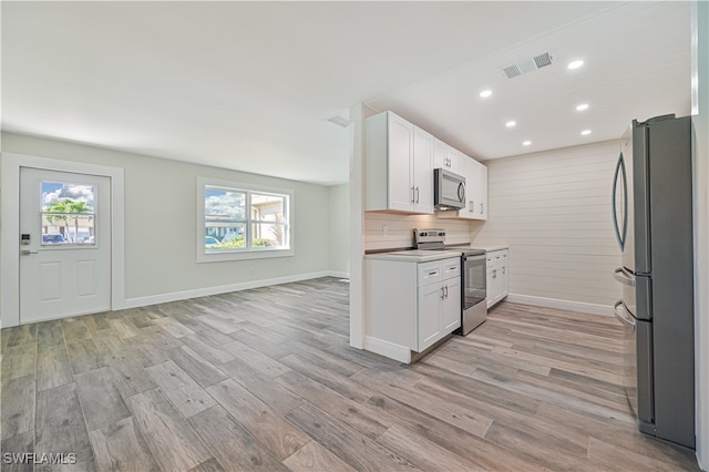 kitchen featuring plenty of natural light, white cabinets, light hardwood / wood-style flooring, and appliances with stainless steel finishes