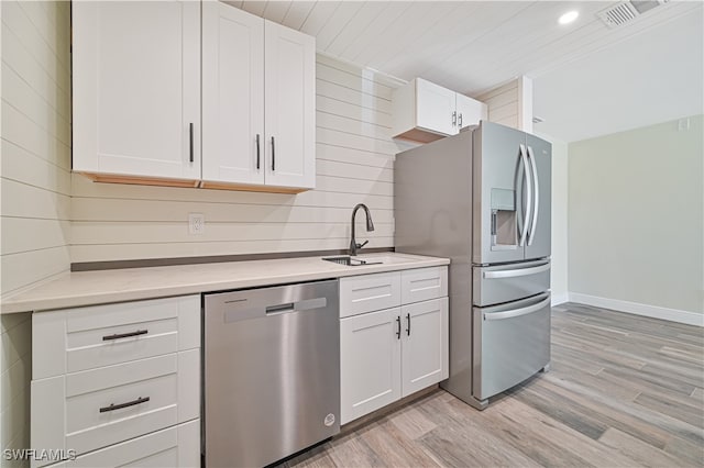 kitchen with sink, white cabinets, light wood-type flooring, and appliances with stainless steel finishes