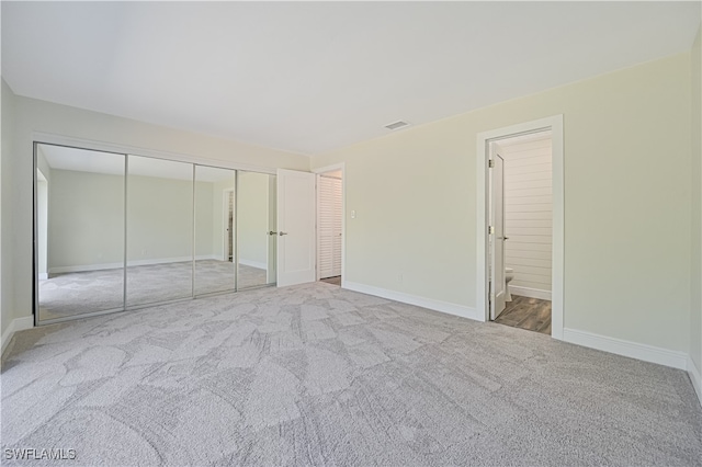 unfurnished bedroom with connected bathroom, a closet, and light colored carpet